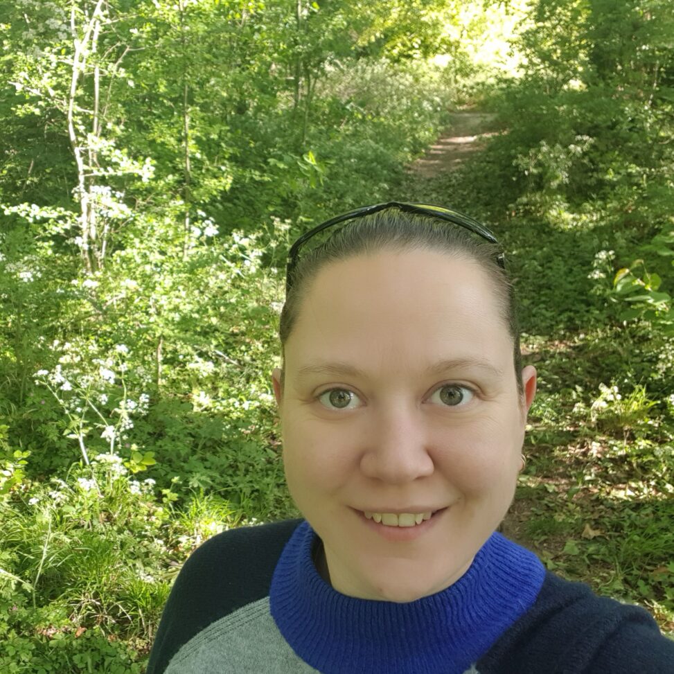 Picture of Nicola Fordham in a wooded rea, loking up at the camera.